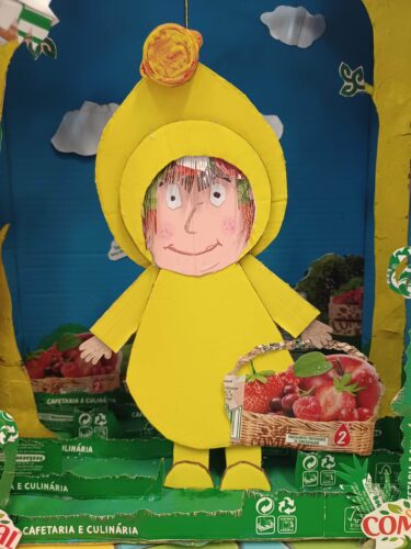 Personagem - A Personagem escolhida foi o Capuchinho Amarelo e foi realizada com cartão, recortes das embalagens da TetraPak da marca Compal, uma tampa da embalagem, cola e maioritariamente tinta amarela.